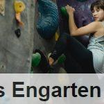 Focused ethnic sportswoman climbing on wall with grips